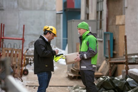 kurer leverer en pakke til en byggeplads