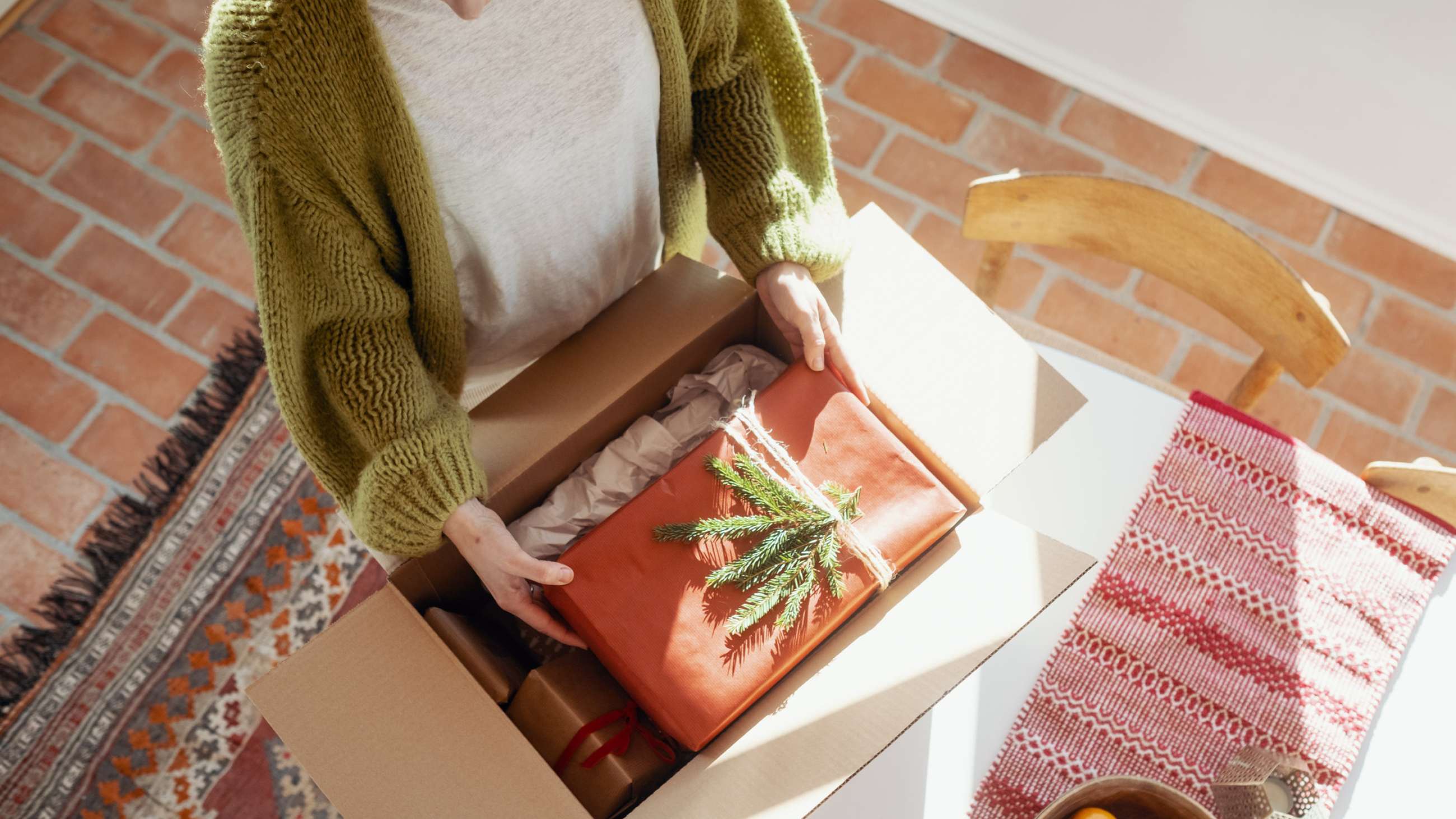 En kvinde lægger en julegave i en pakke.