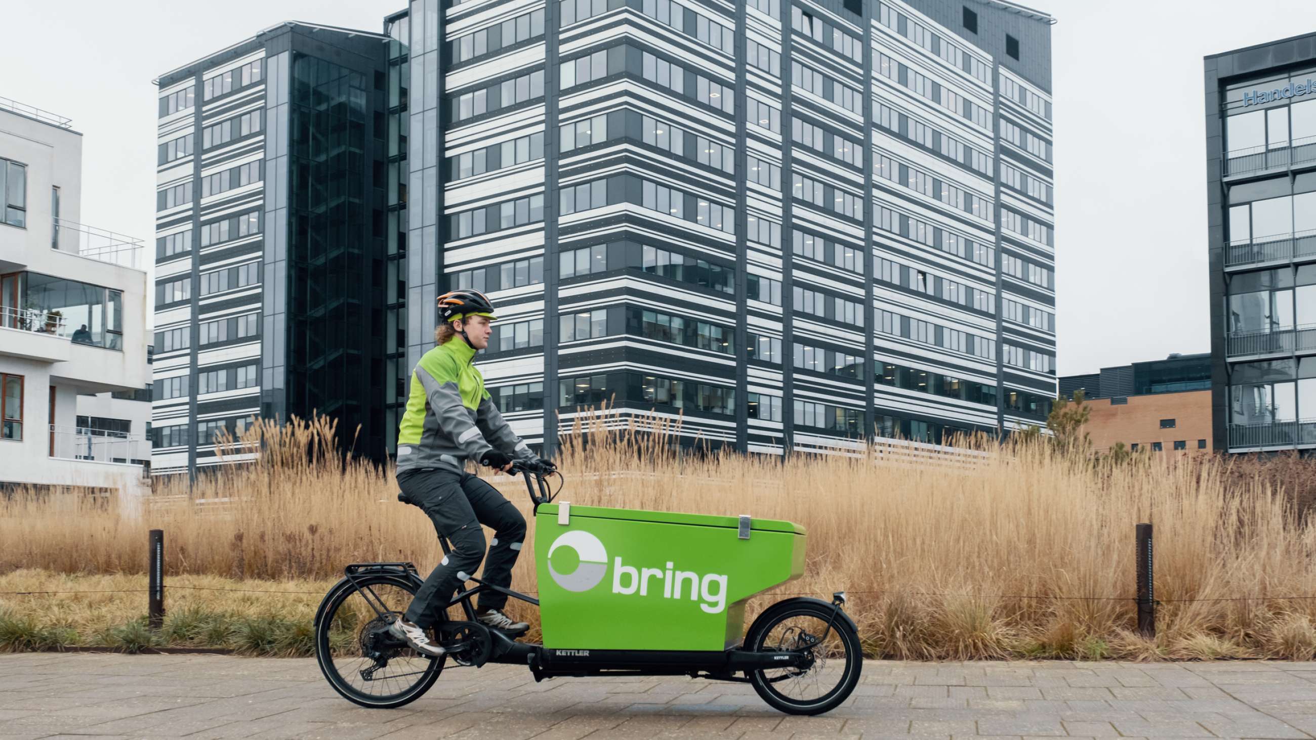 Bringbud på grøn elcykel transporterer pakker i et boligområde.
