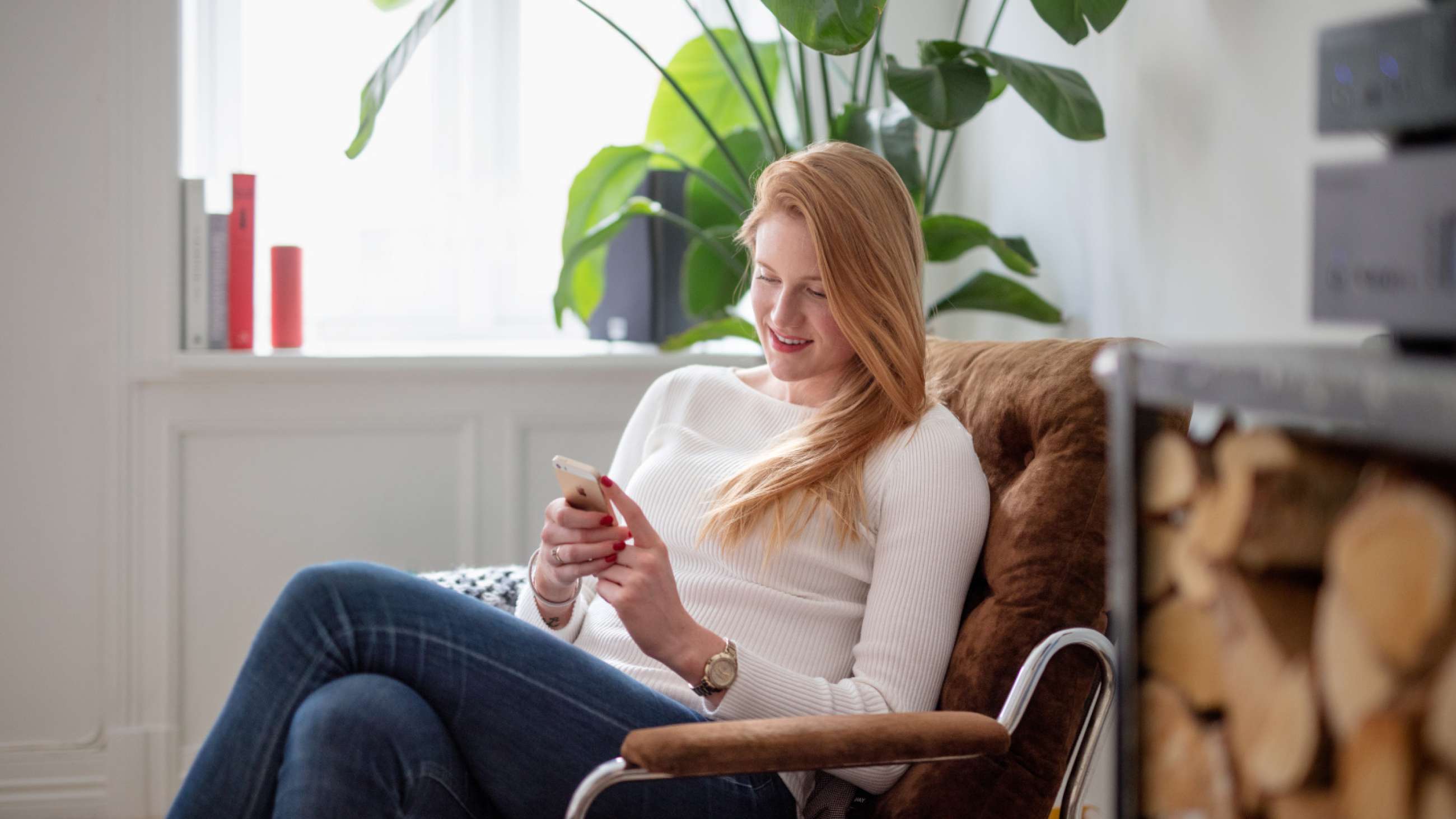 Kvinde med mobiltelefon i lænestol