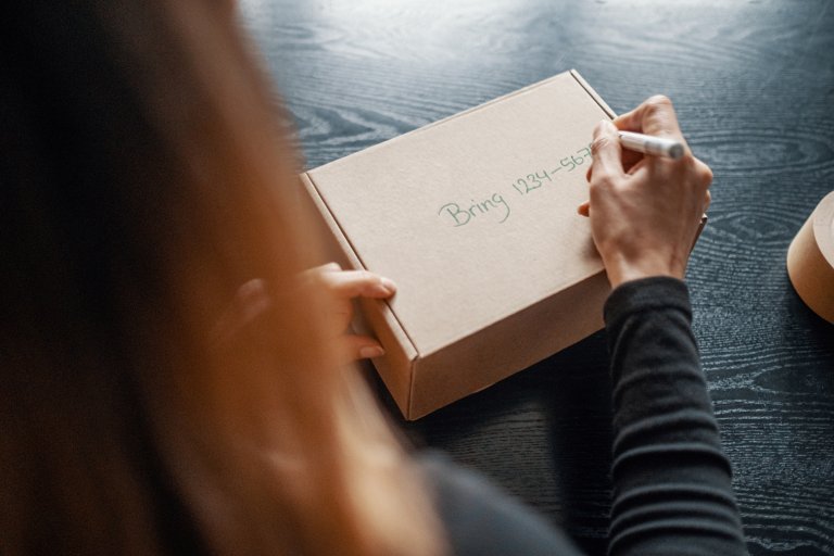En kvinde skriver en pakkekode på en pakke.