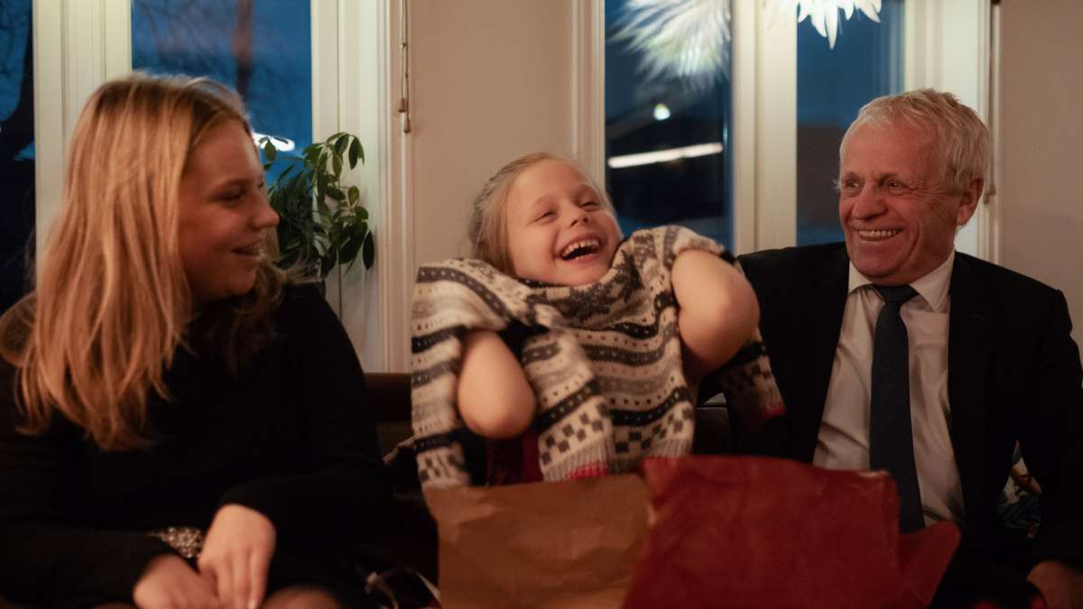  Glad pige åbner julegave købt på Black Friday sammen med sin bedstefar og søster