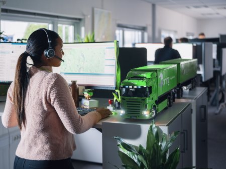 En medarbejder hos Bring kundeservice står foran en computer med et headset på hovedet