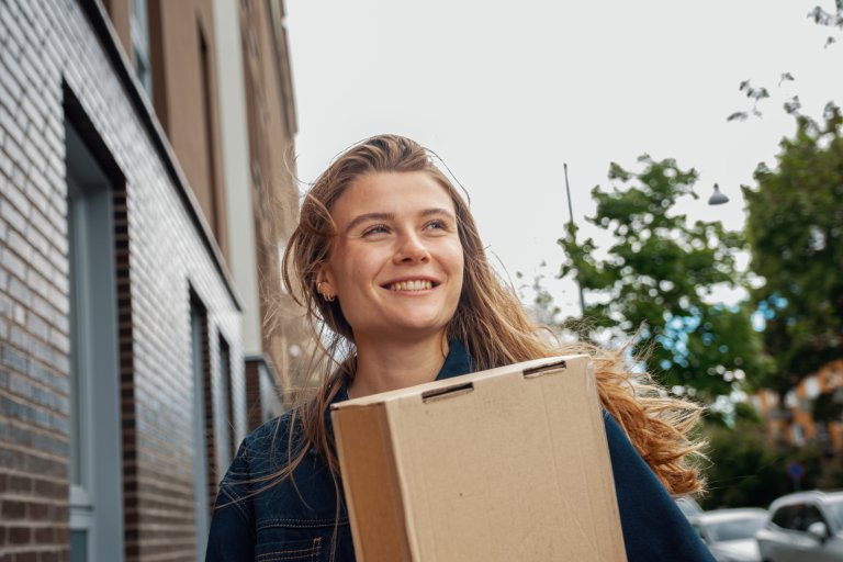 En kvinde smiler med en pakke i hånden