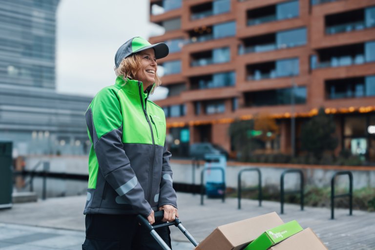 En kvindelig Bringbud trækker en vogn med pakker på gennem byen