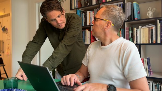 To mænd står ved en computer og taler