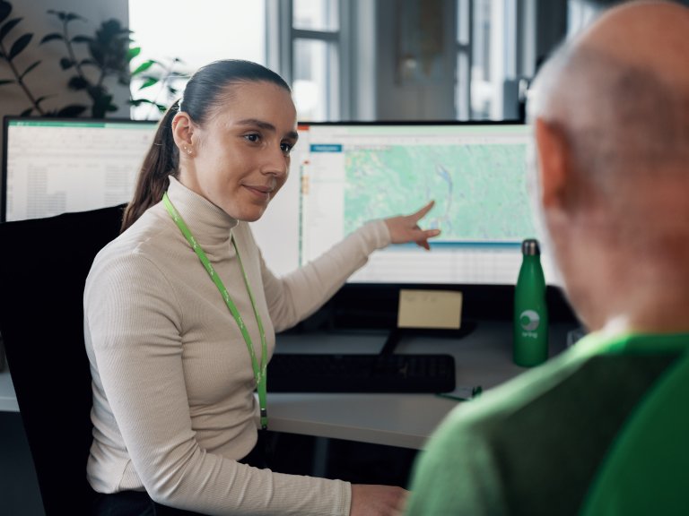En kvindelig medarbejder hos Bring sidder foran en computerskærm sammen med en kunde
