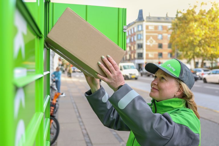 Bring-chauffør med pakke ved pakkeboks