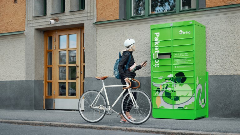 Pige med cykel henter en pakke fra en pakkeboks