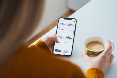 En kvinde har en mobiltelefon i hånden med en webshop og handler online