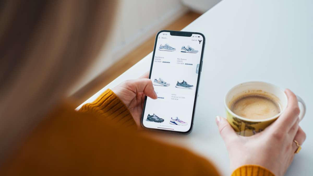 En kvinde har en mobiltelefon i hånden med en webshop og handler online