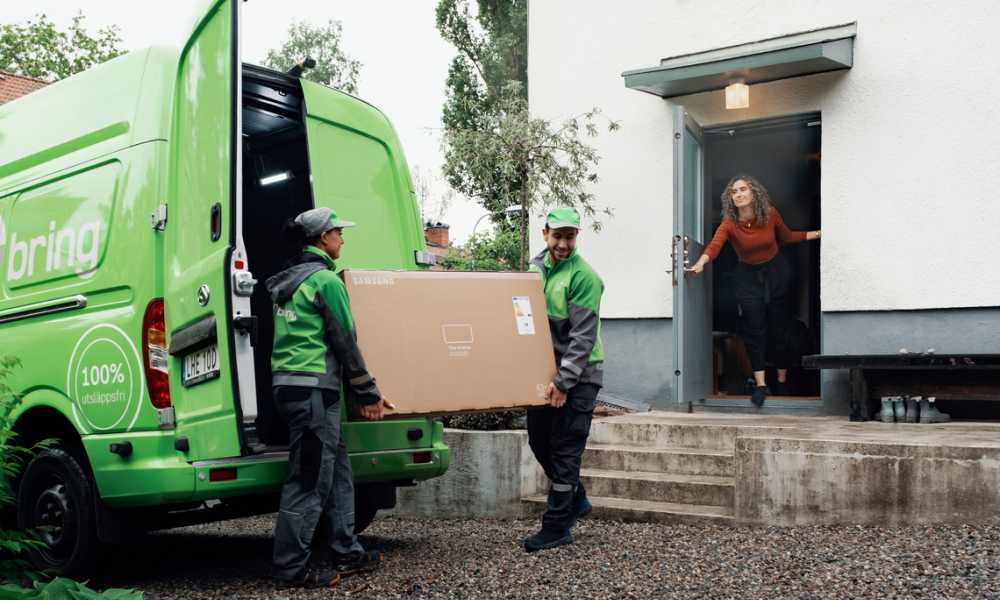 2 Bring chauffører bærer en stor og tung pakke til en kvinde i et hus