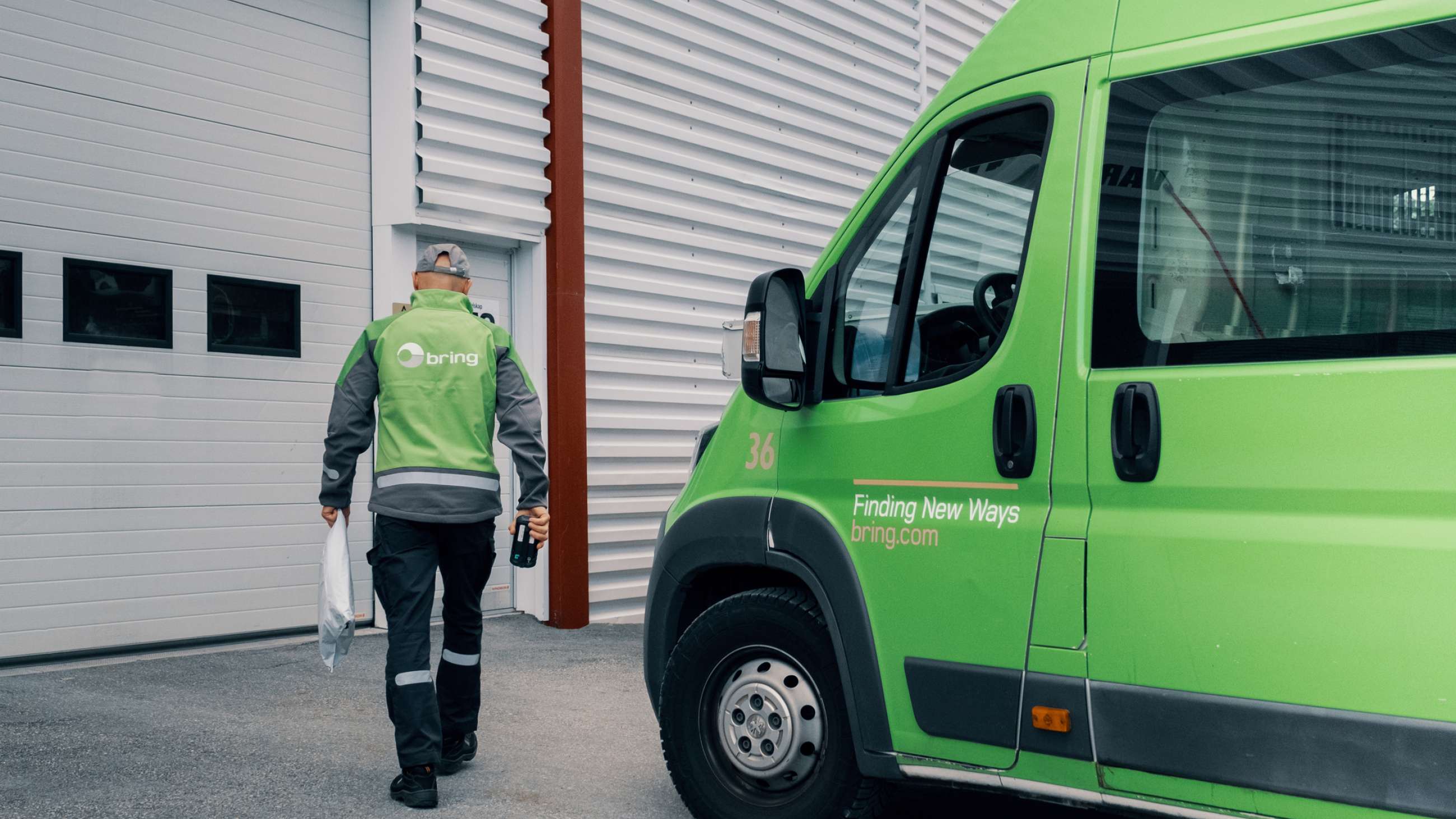 Et Bringbud bevæger sig mod en virksomhed med en levering foran en Bring varebil